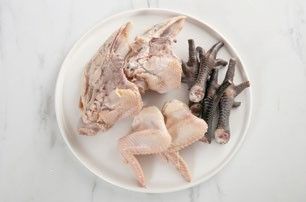 將雞骨架及雞爪、雞翅用熱水汆燙、洗淨，撈出瀝乾