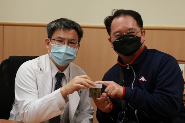 余政展主任（左）拿著膽囊取出的一整瓶膽結石，叮嚀回診病人清淡飲食保健康。